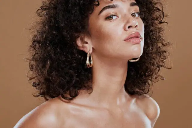 Curly-haired woman wearing gold hoop earrings